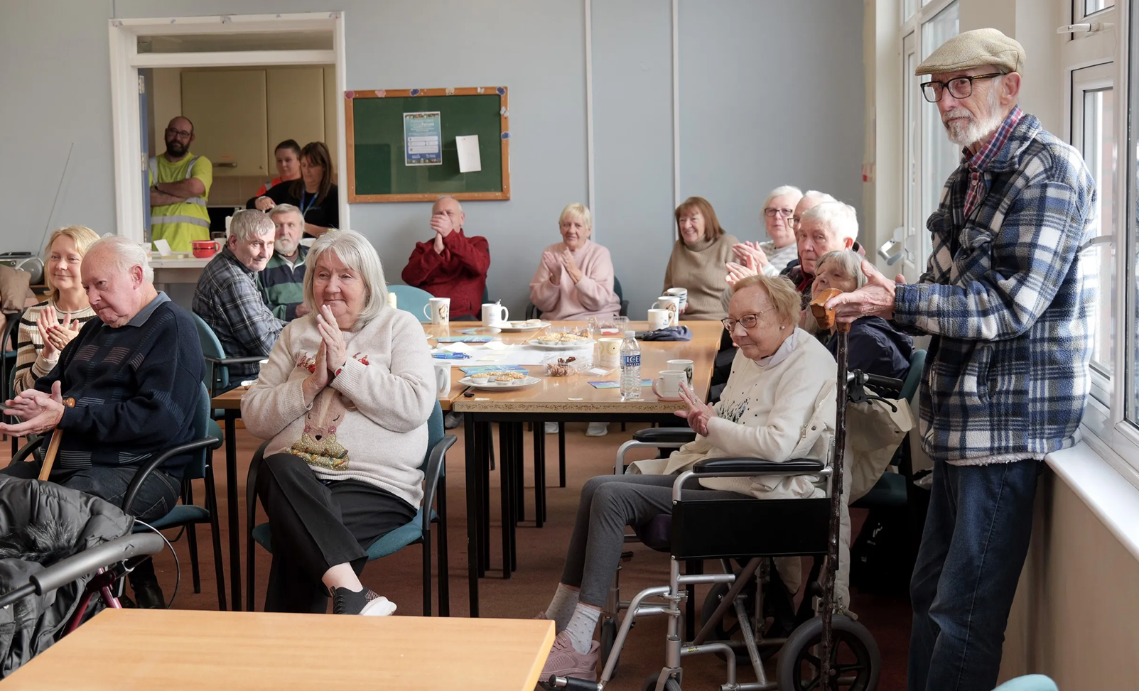 Group of people sat around tables in a community centre