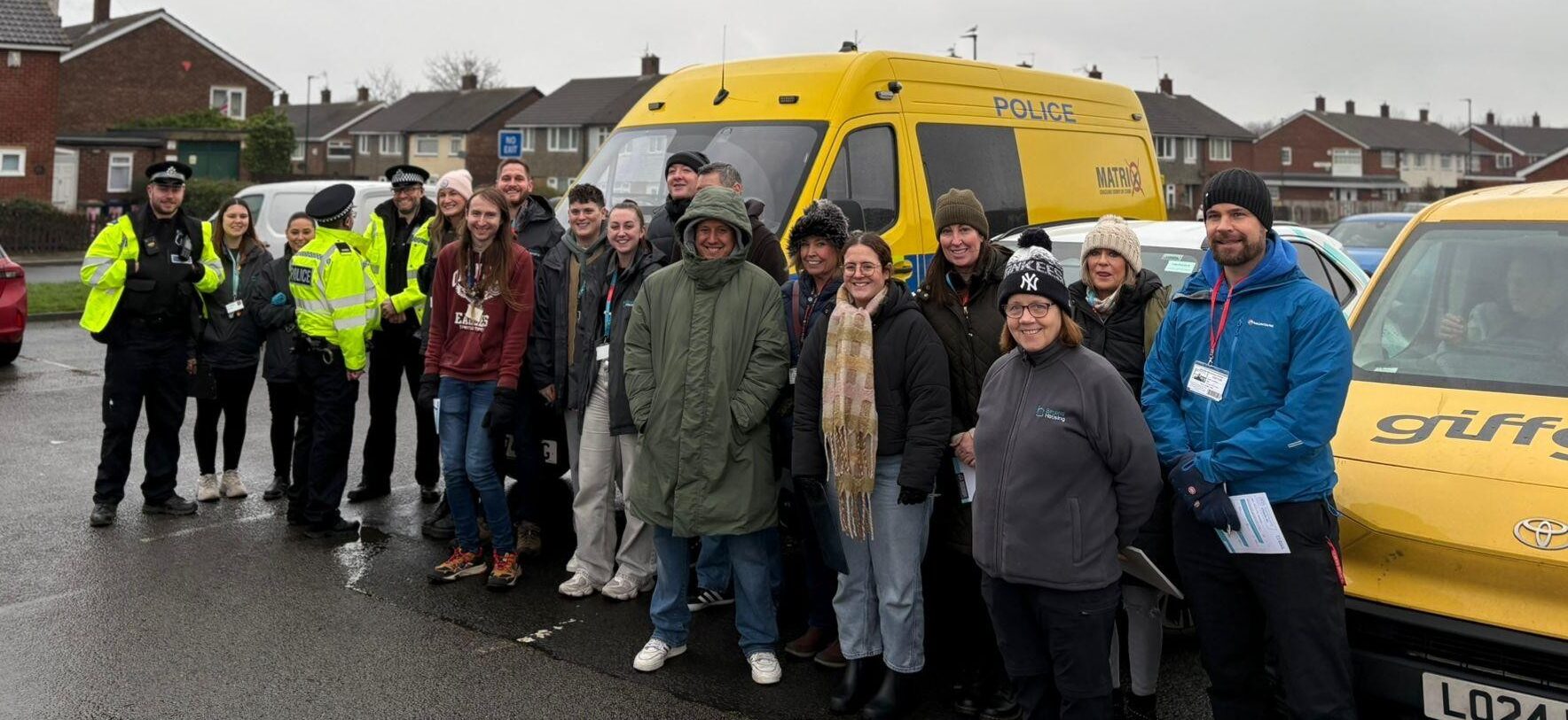 Big group of pople stood in front of poilice vans