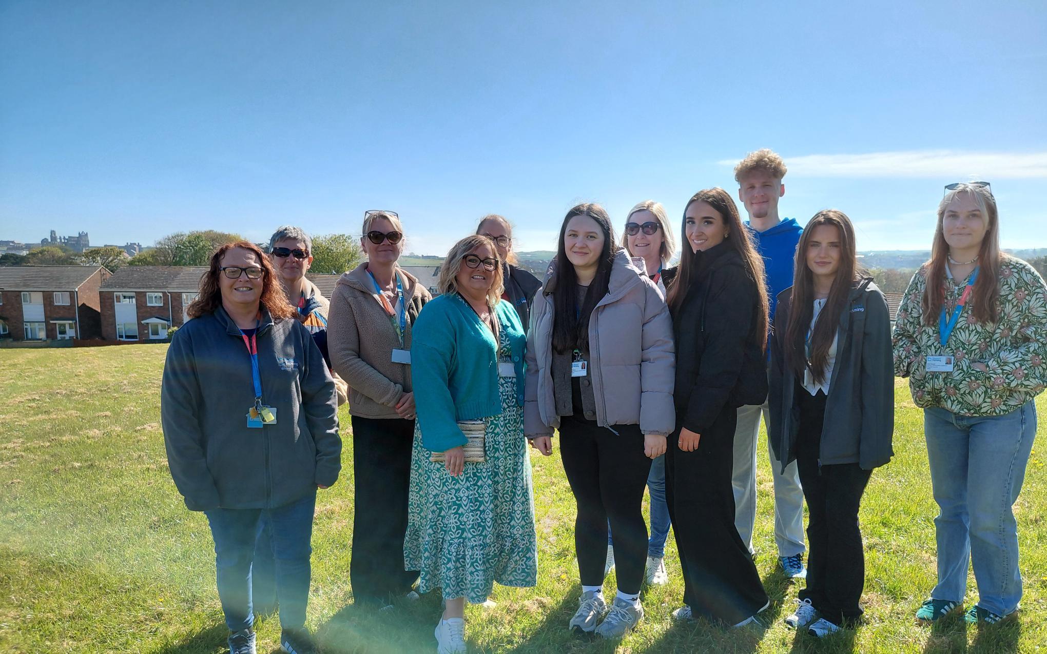 Twelve people stood outside, Whitby Abbey in the background