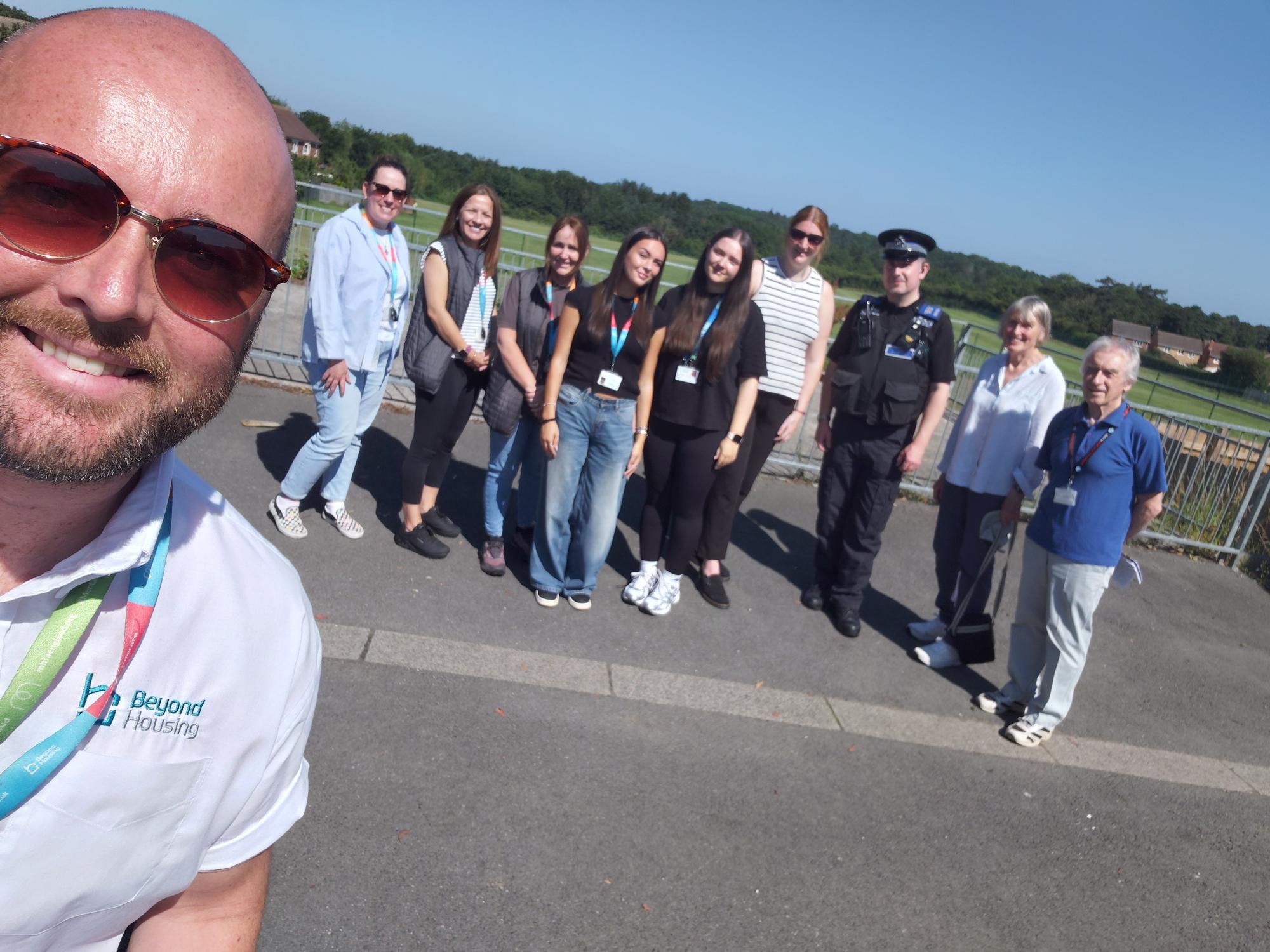 Person taking selfie in foreground, and nine people grouped in the background