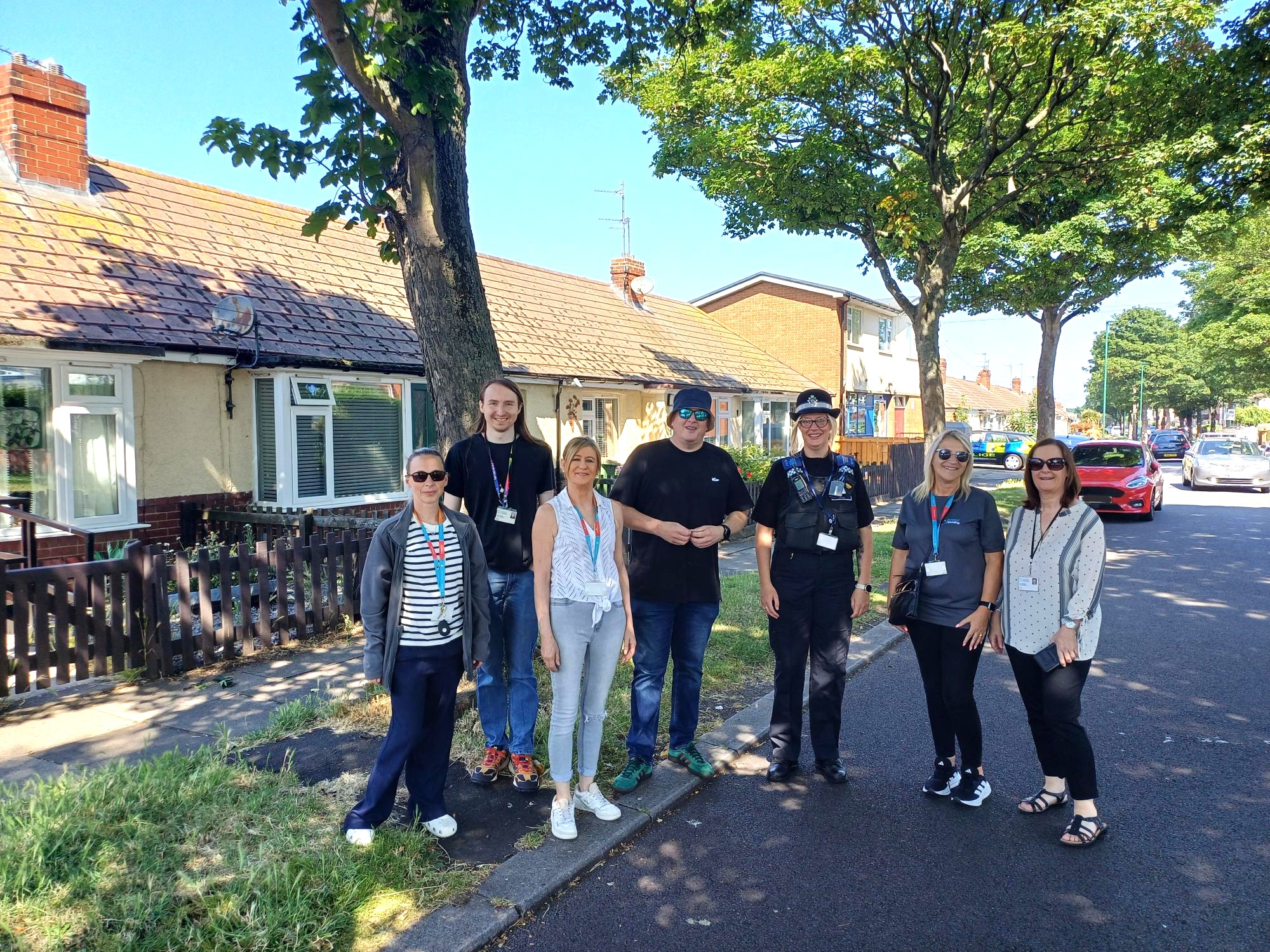 Seven people stood on a tree-lined street