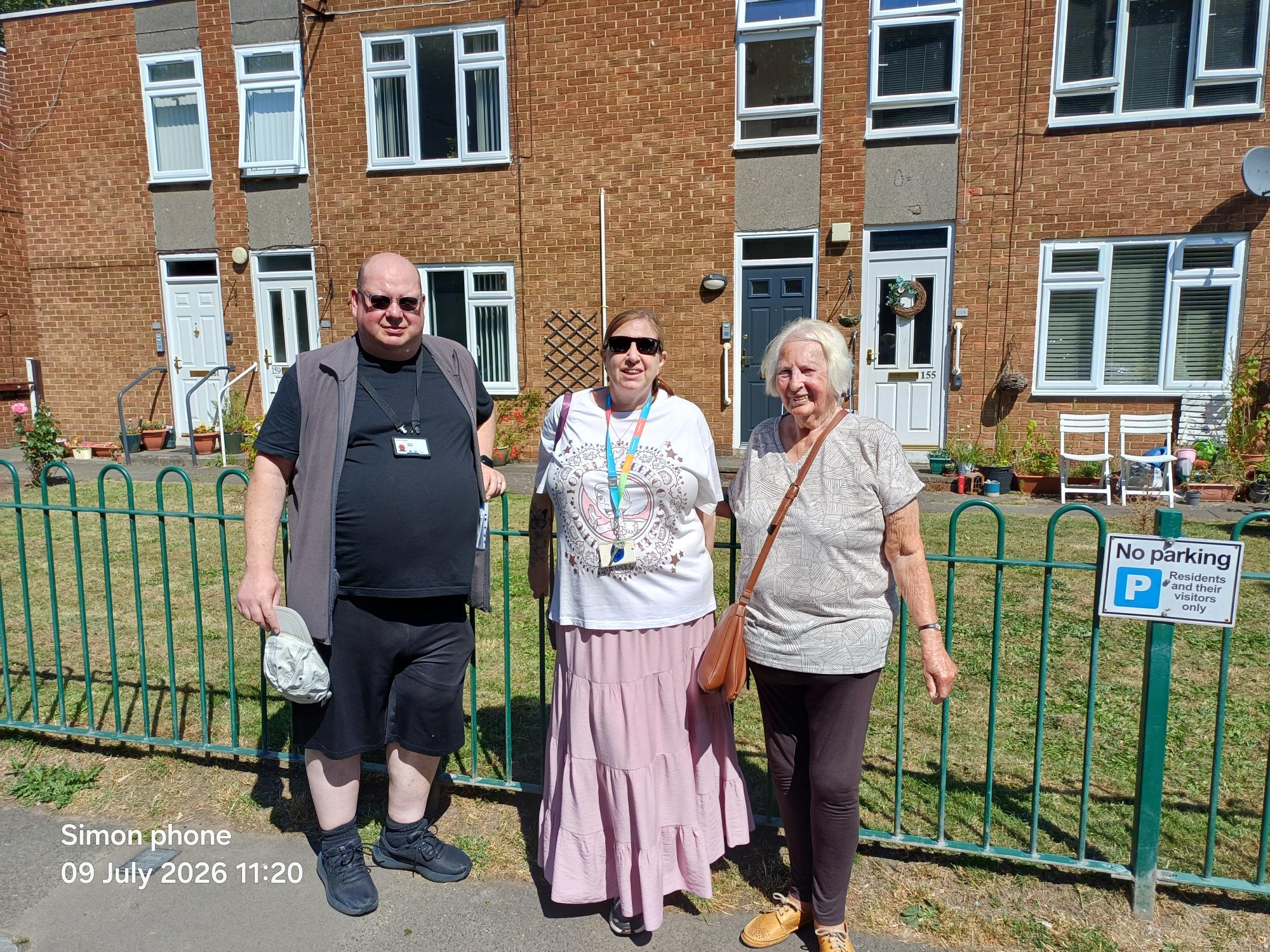 Three people outside a block of flats